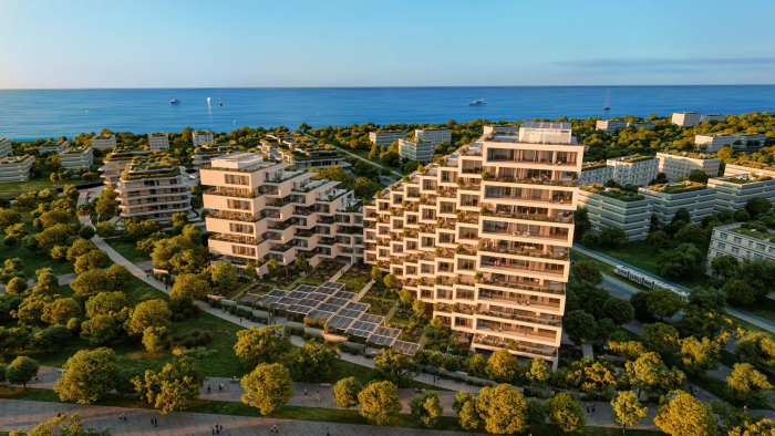 Contemporary apartment complex surrounded by trees. Solar panels at the front, the sea in the background.